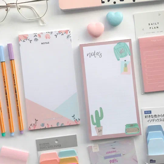 Printed notepads and sticky memos laid out on a desk with pens