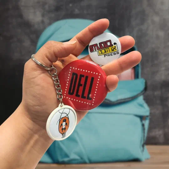 Printed pin buttons and a round keychain held in one hand
